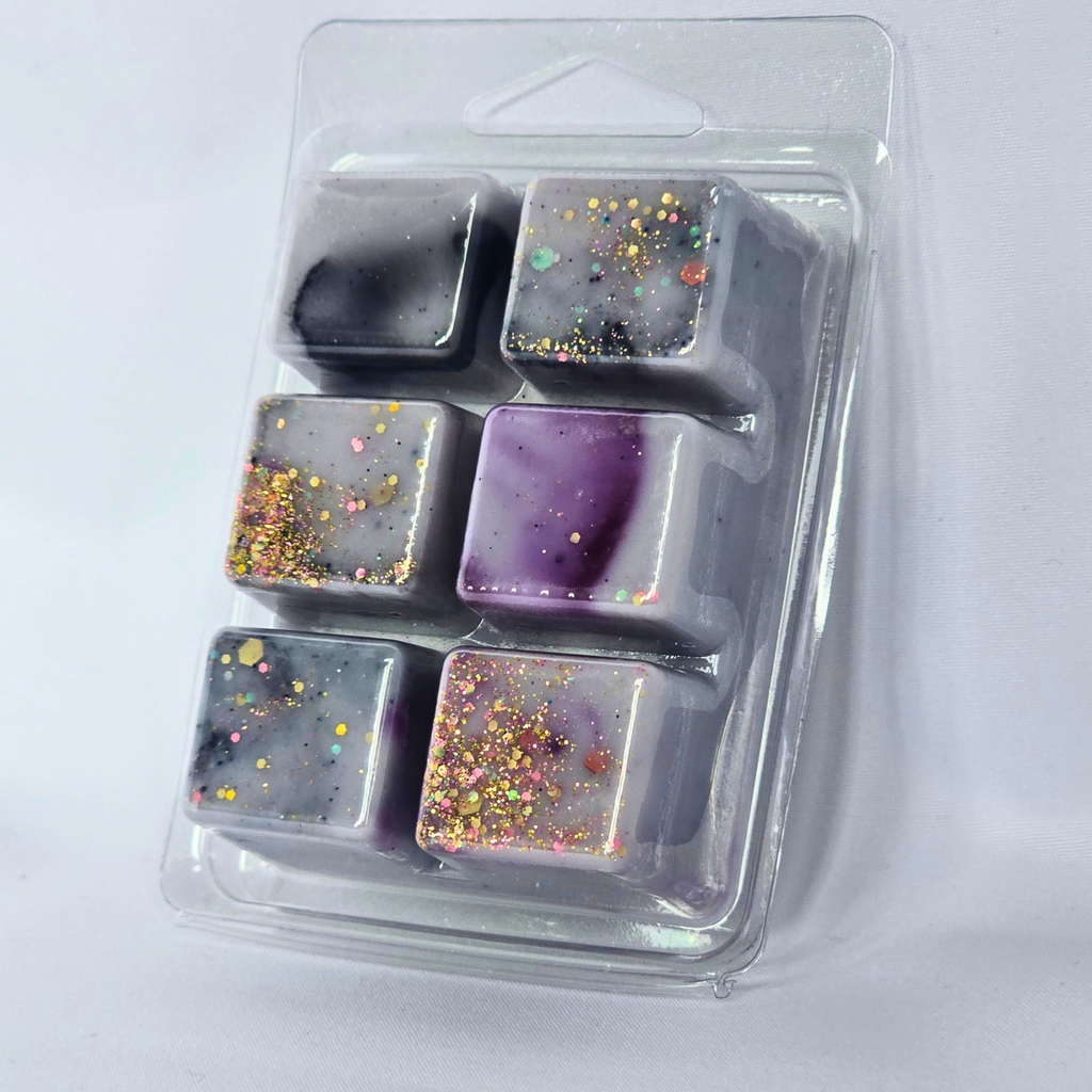 Six square decorative wax melts or soap cubes in a clear plastic clamshell package, featuring marbled gray, purple, and black patterns with gold glitter accents.