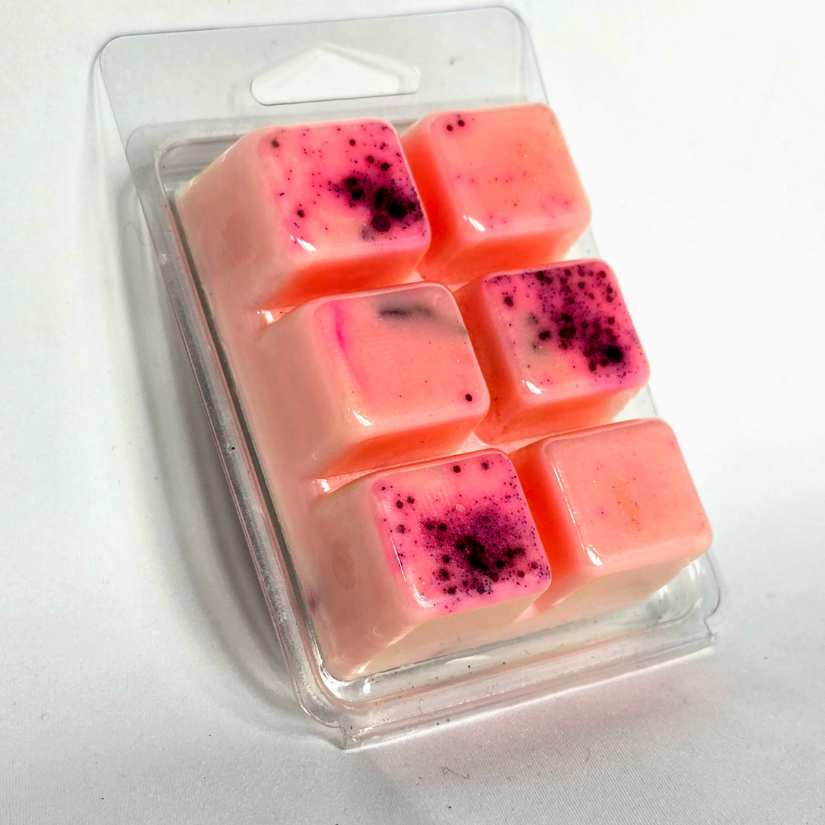 Six pink wax melts with dark purple speckles, packaged in a clear plastic clamshell blister pack on a white background.